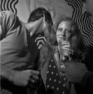 Image of man whispering to a women with a drinl