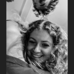 Shot from below of a girl smiling at the camera leaning on another girl who is looking away