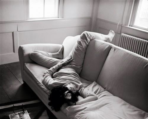 Woman lies sprawled across a sofa.